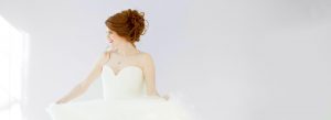 women in bridal gown with curly updo and side part against white background