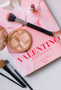 Overhead Shot of Guerlain Bronzer, Makeup Brushes and Valentino Book